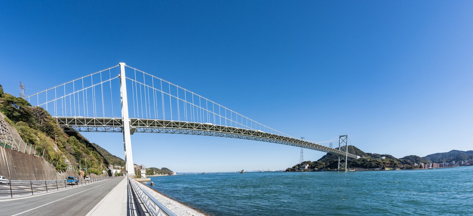 橫跨關門海峽的關門橋吊橋，連接本州的下關與九州的門司，襯著藍天與海