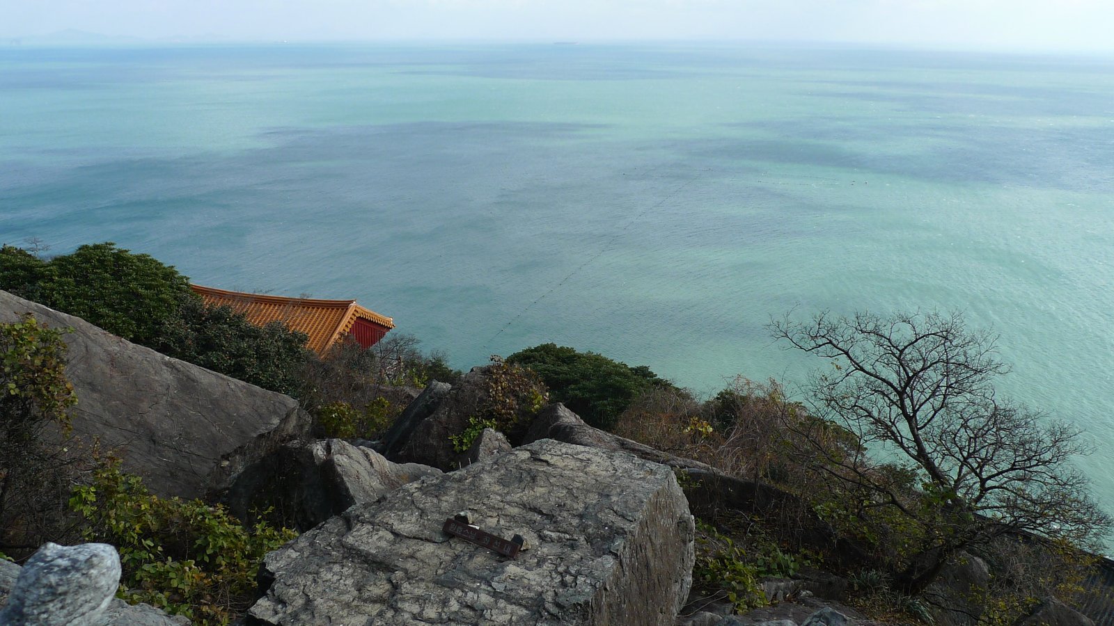 從向日庵俯瞰金鰲山岩石與南海的遼闊海面，左側可見寺院屋頂