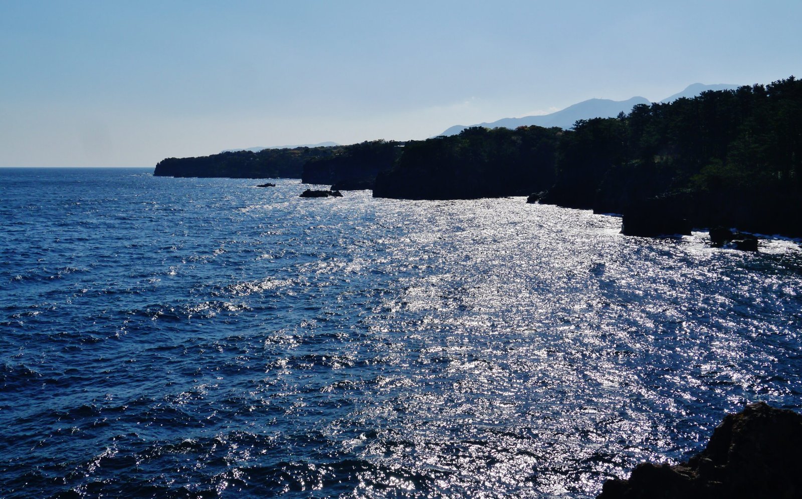 城崎海岸夕照下波光粼粼的海面與黑色熔岩懸崖