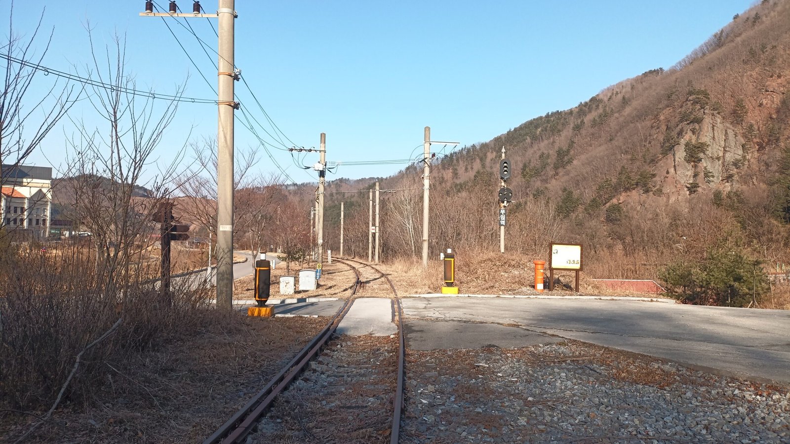 三陟心浦里舊永東線鐵軌蜿蜒穿過山谷，兩旁立著號誌燈與平交道標誌