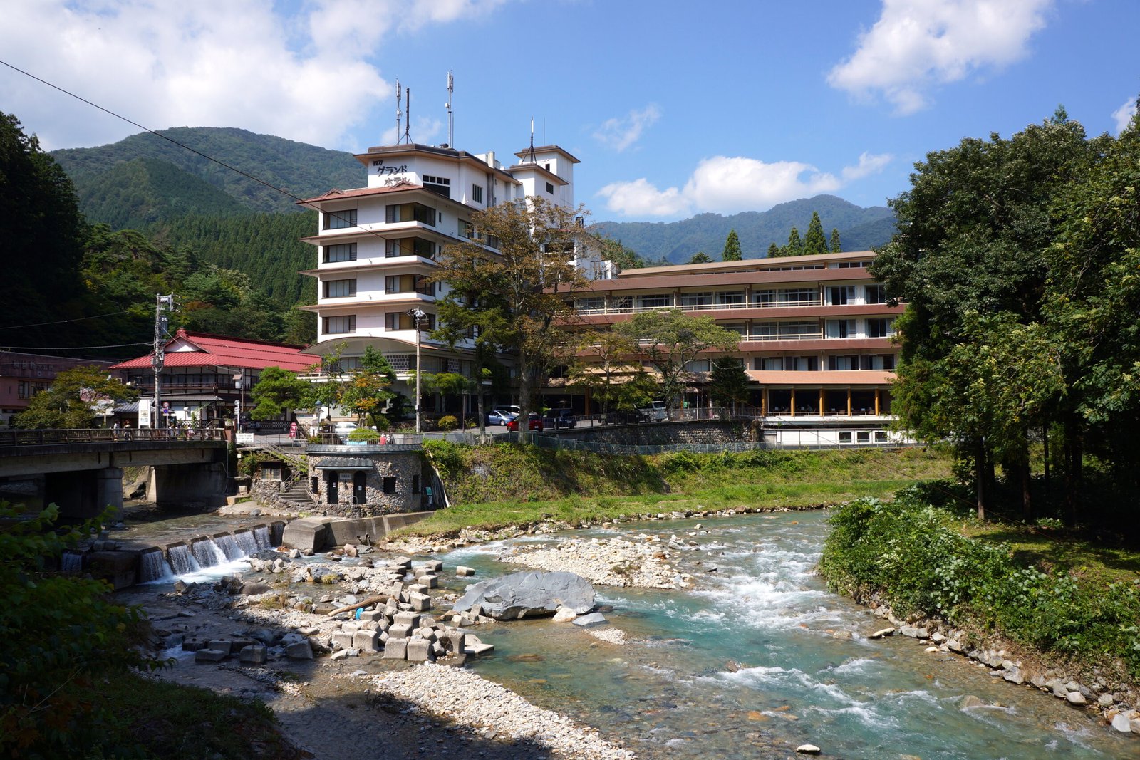 四萬溫泉溫泉街，河畔旅館建築與群山綠意環繞