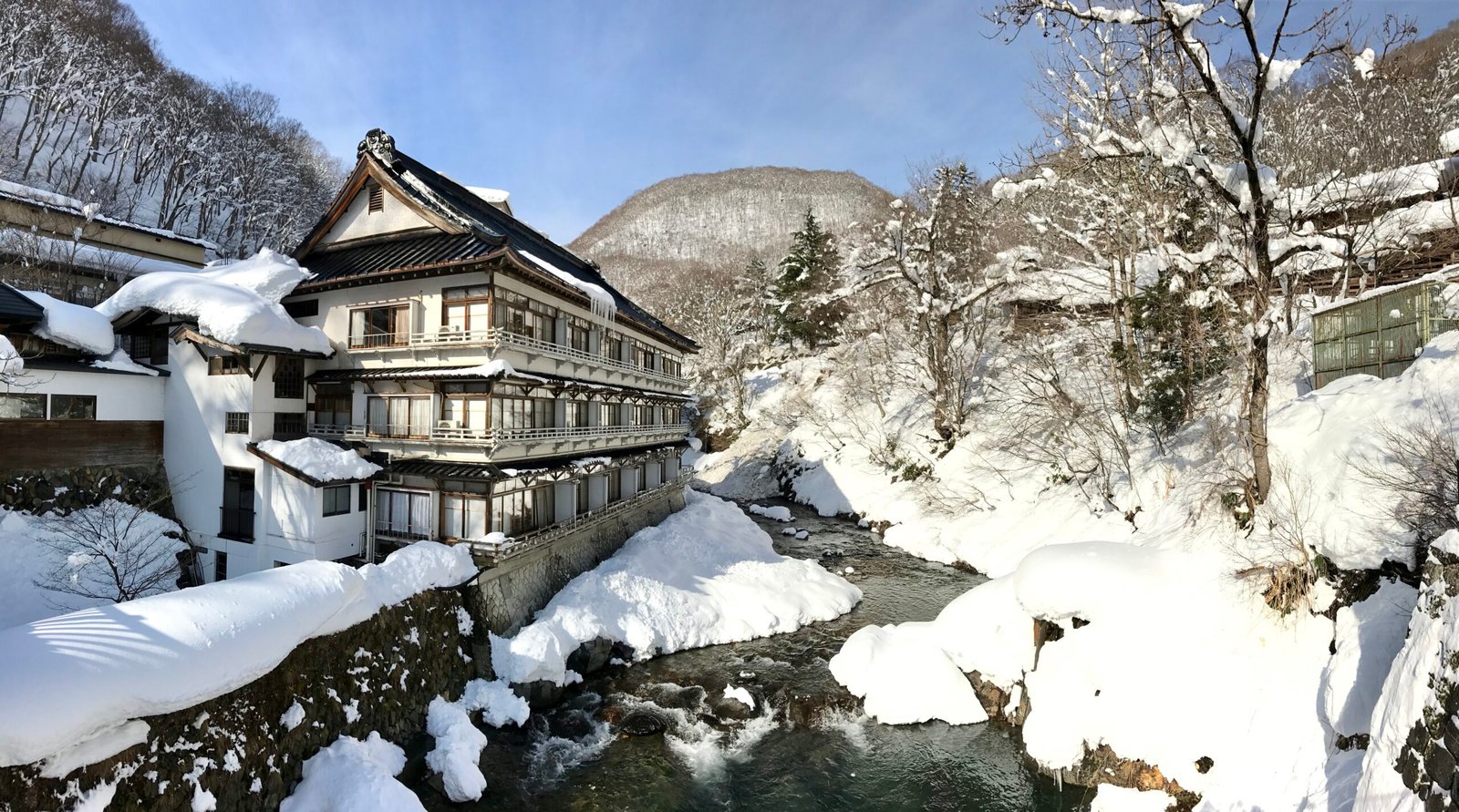 冬季積雪中的寶川溫泉汪泉閣木造旅館與寶川溪流