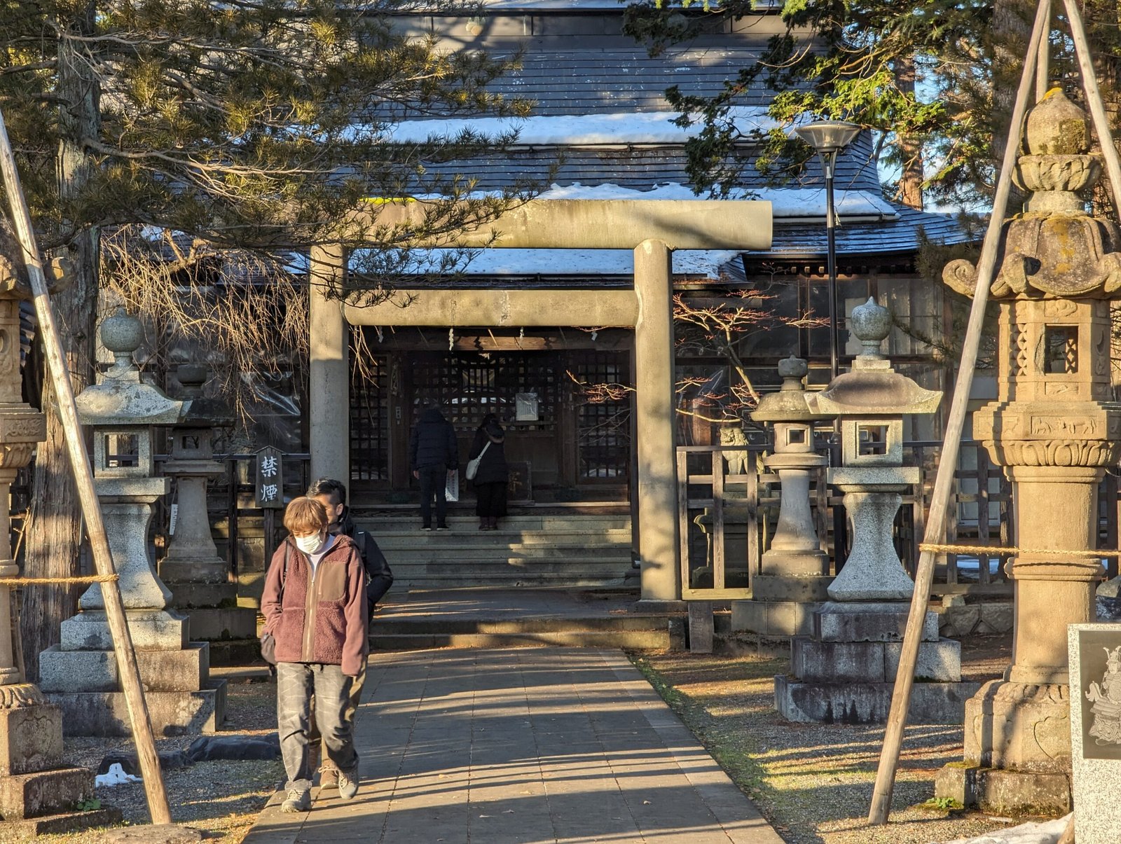 冬日陽光下米澤上杉神社的石鳥居與石燈籠參道